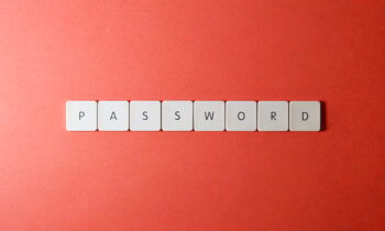 Tessere del gioco "Scarabeo" che compongono la parola password su sfondo rosso, immagine che introduce il tema dell'importanza di scegliere password sicure.