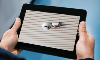 Mani che tengono un tablet che consente il controllo da remoto dei sistemi antincendio come avviene grazie all'App Inim Cloud Fire.