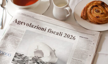 Primo piano della pagina di un quotidiano che riporta un articolo sulle agevolazioni fiscali in corso, fra cui rientra il Bonus Sicurezza 2026. Vicino al giornale, sul ripiano del tavolo, sono appoggiate una tazza di the, una lattiera e un piattino con una brioche.