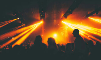 Interno di un locale di intrattenimento con luci giallo-arancio puntate sulla folla, immagine che introduce il tema della sicurezza antincendio nei locali pubblici.